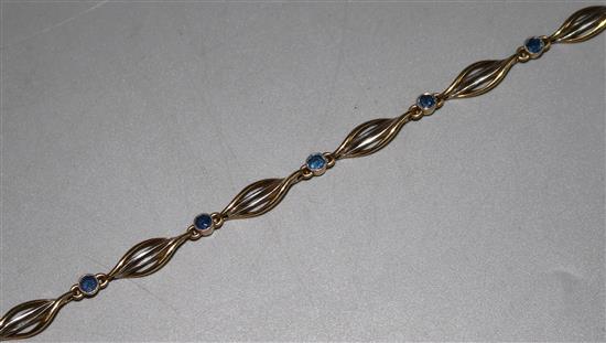 An 18ct two colour bracelet set with seven sapphires, 7in.